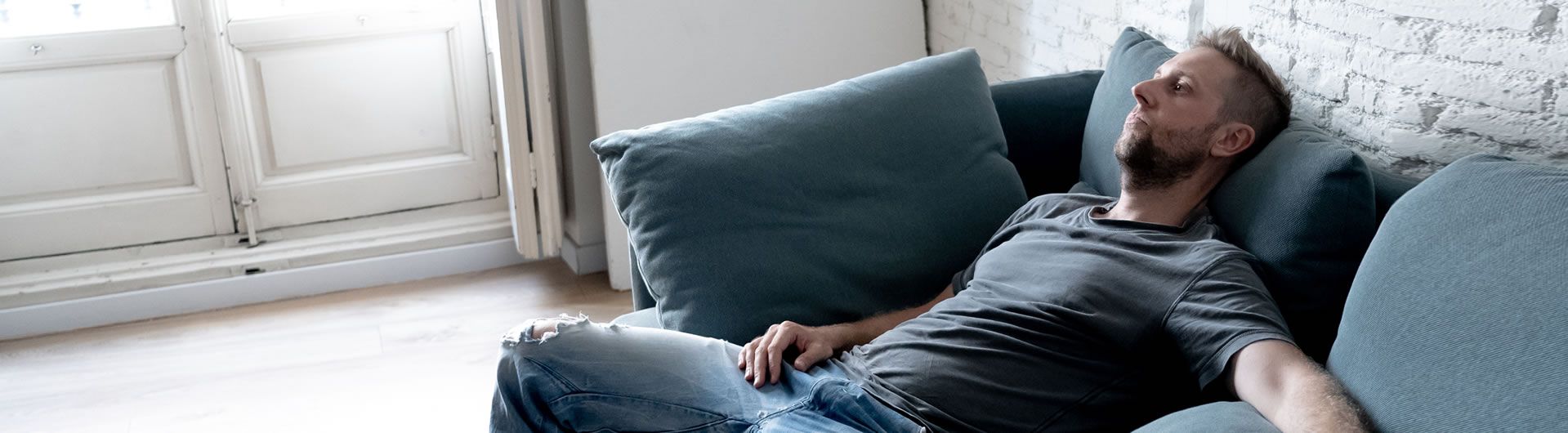Depressed young man on blue sofa
