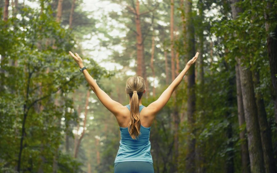 girl with arms outstretched in forest